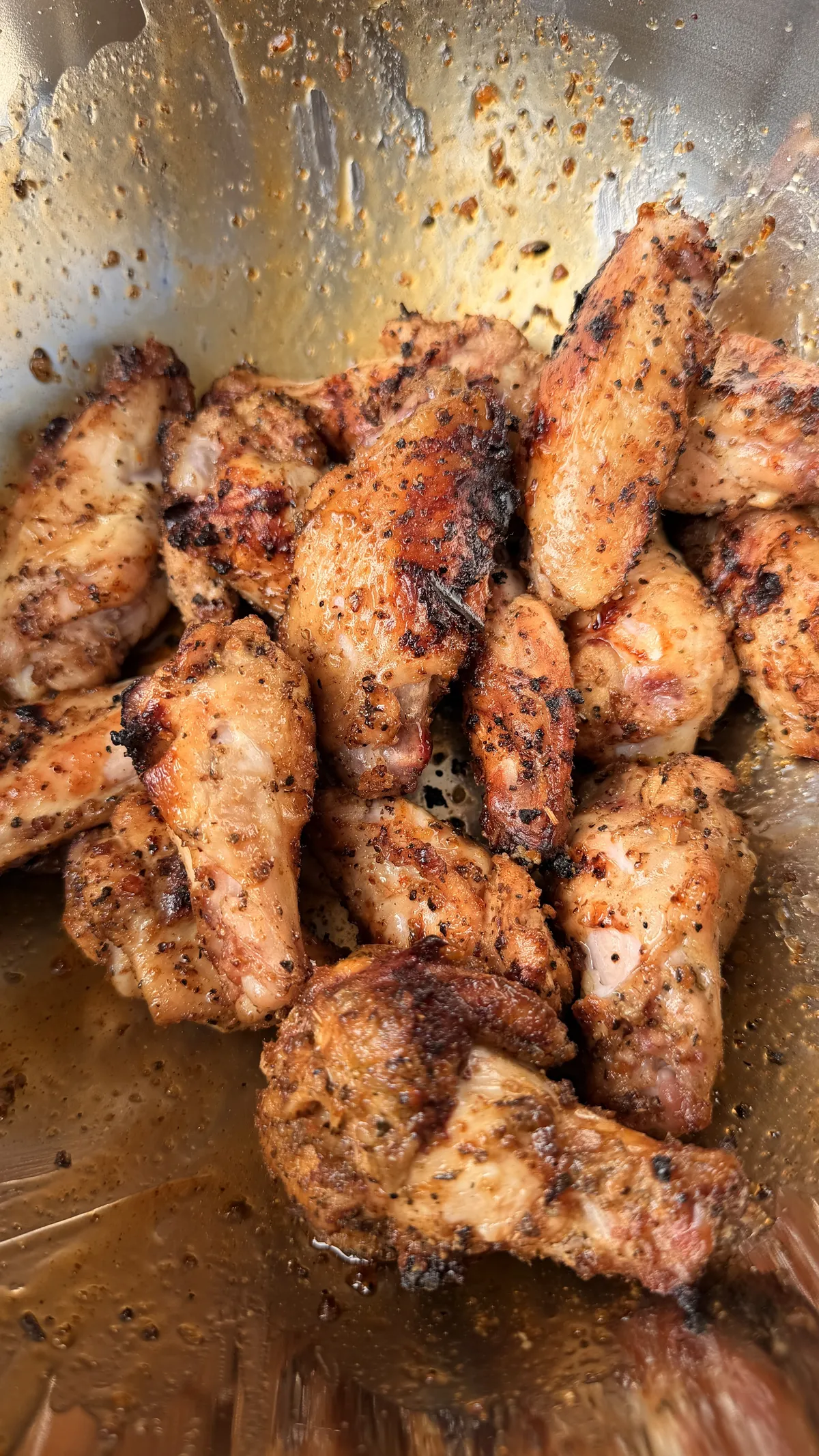 Grilled chicken wings seasoned with Cajun, lemon pepper, and Dano's dry rub, charred and crispy in a metal bowl