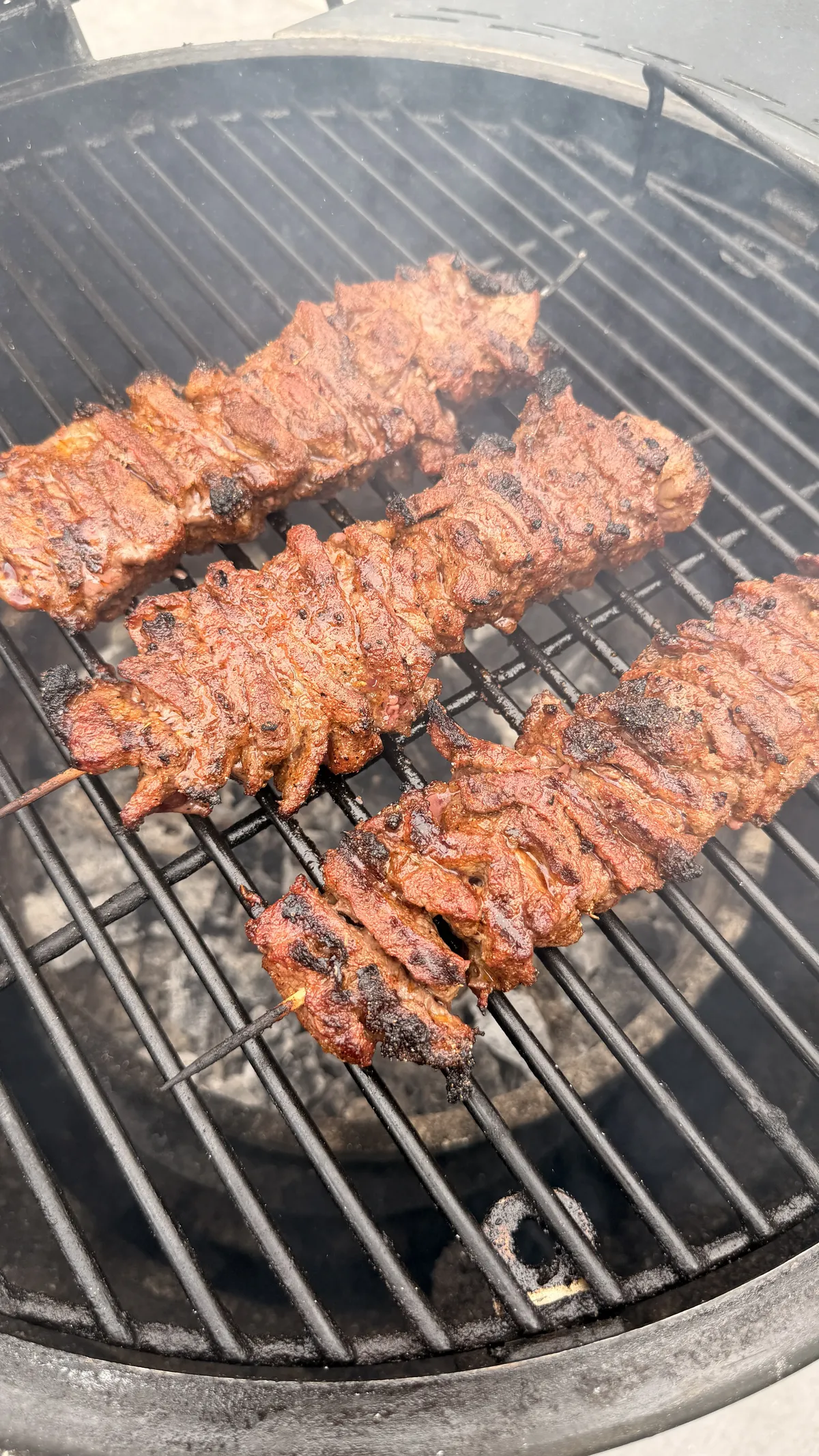 Seasoned tri-tip skewers cooking over direct heat on a charcoal grill at 400–450°F