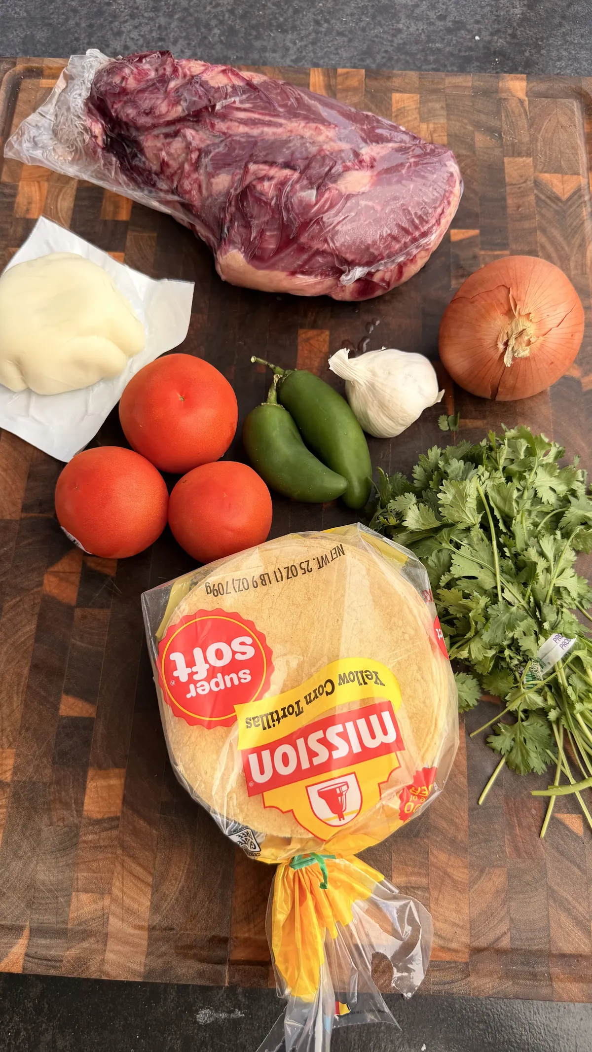 Tri tip tacos ingredients: whole tri-tip, Oaxaca cheese, Roma tomatoes, jalapeños, garlic, onion, cilantro, and Mission corn tortillas