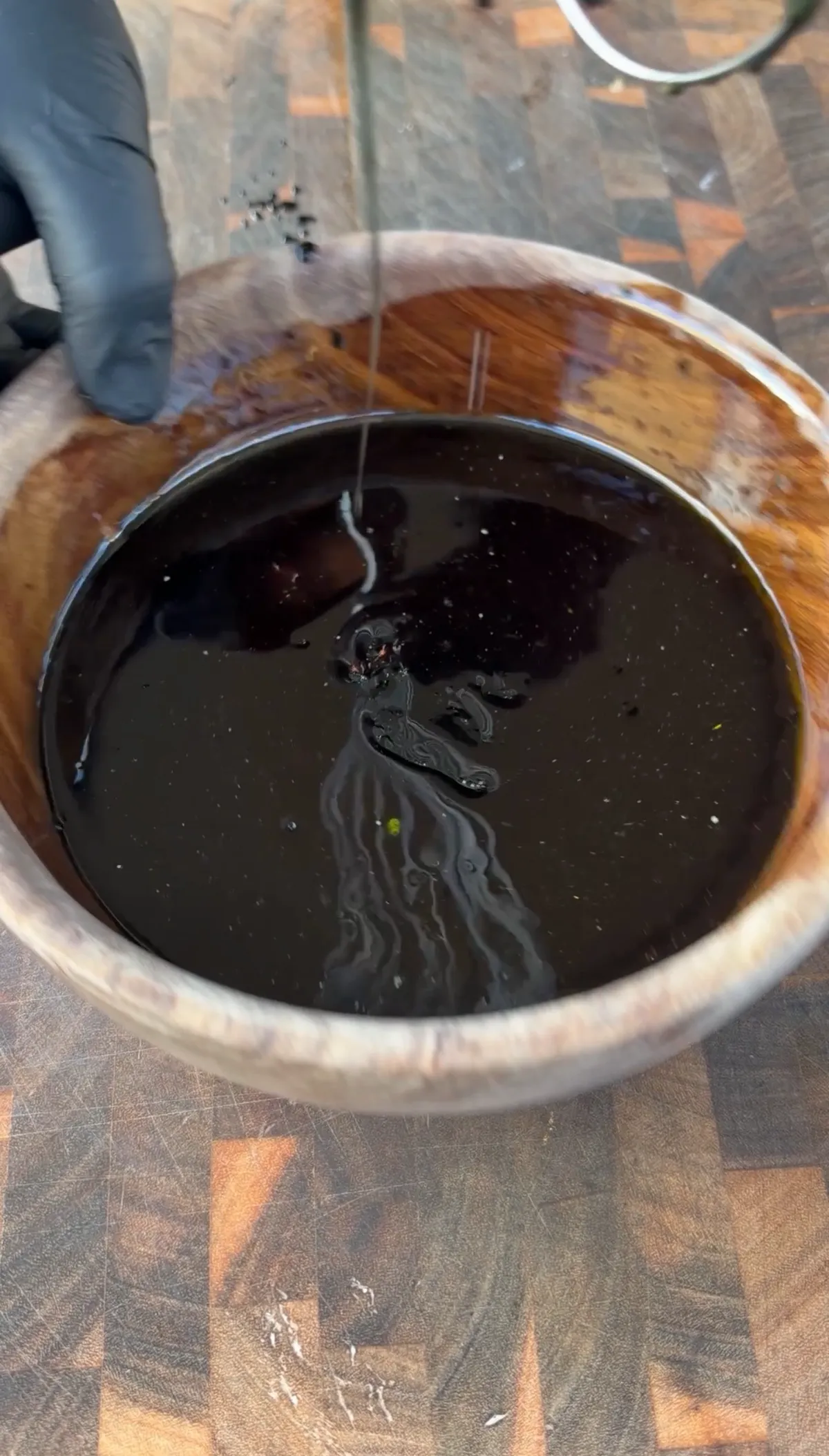 Black marinade with soy sauce, honey, chili paste, and black food coloring in a wooden bowl