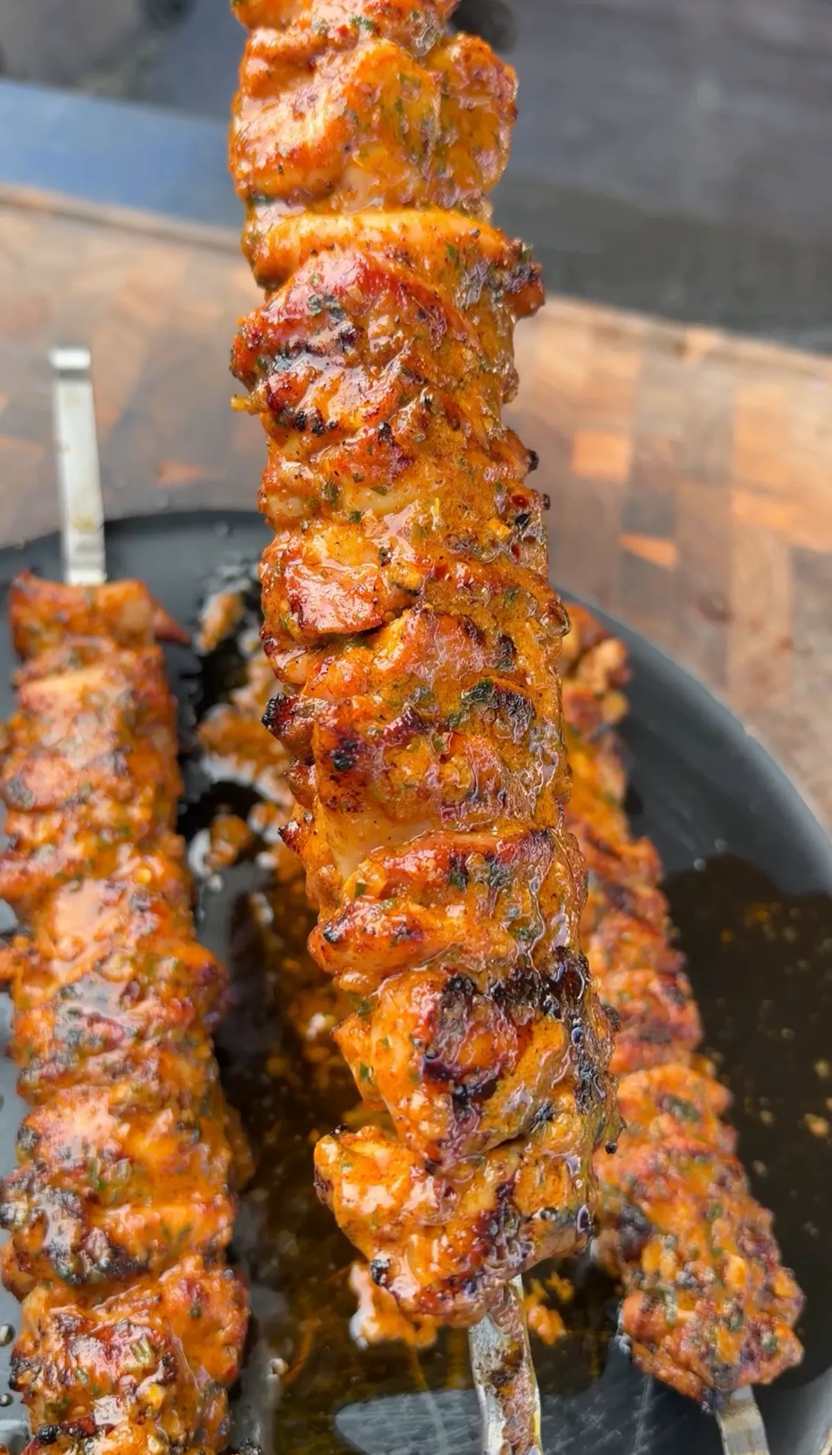 Close-up of juicy grilled chicken thigh skewers coated in garlicky cowboy butter with visible parsley and char marks