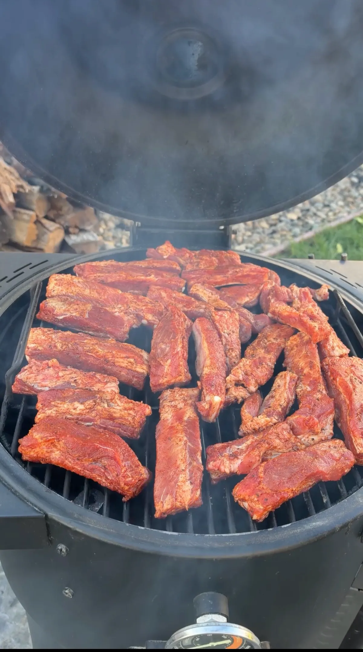 Individual St. Louis-style pork ribs coated in cherry barbecue rub smoking on round smoker grates at 300–350°F