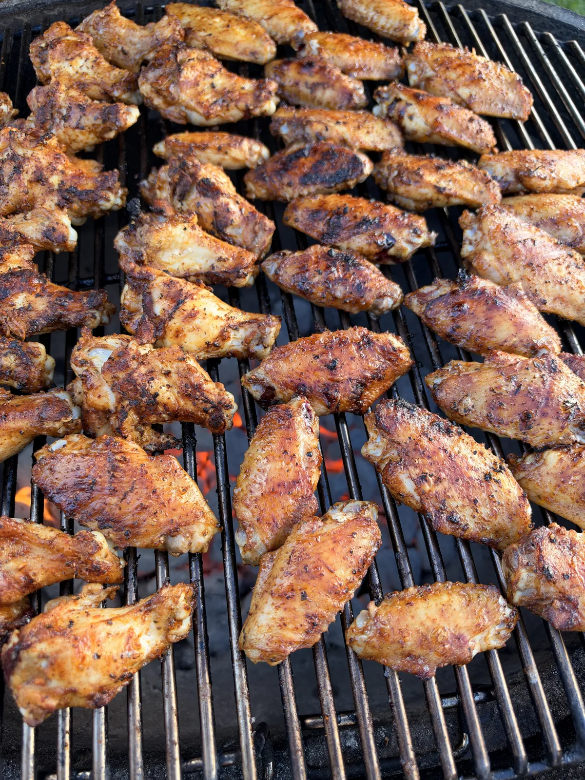 Chicken wings seasoned with poultry seasoning grilling over open flame on a charcoal grill at 300–350°F