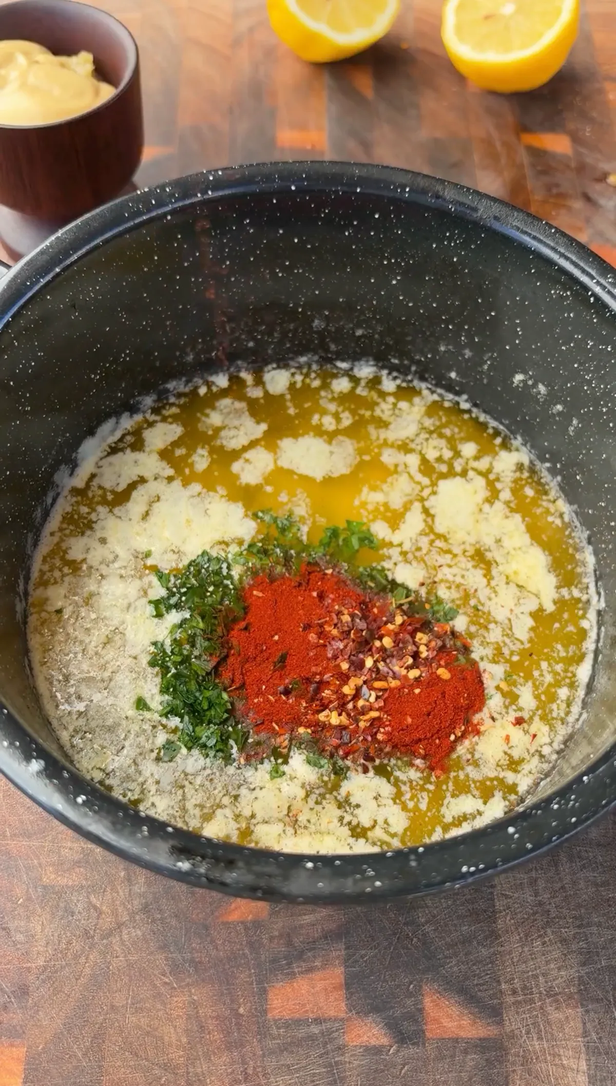 Melted butter, minced garlic, paprika, red pepper flakes, and parsley combined in a dark mixing bowl for cowboy butter