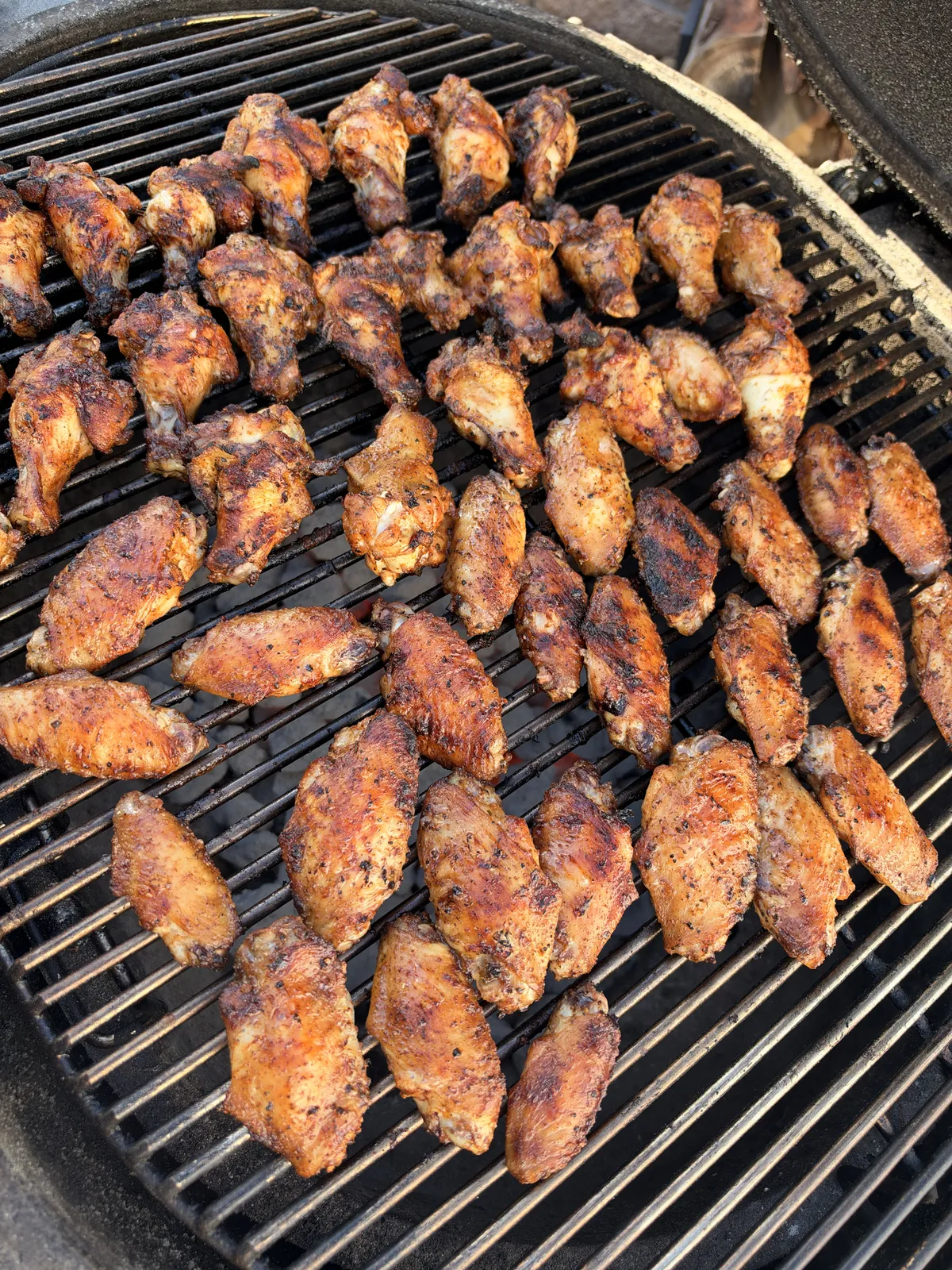 Chicken wings seasoned with poultry seasoning grilling at 300–350°F on charcoal grill grates until skin is crispy