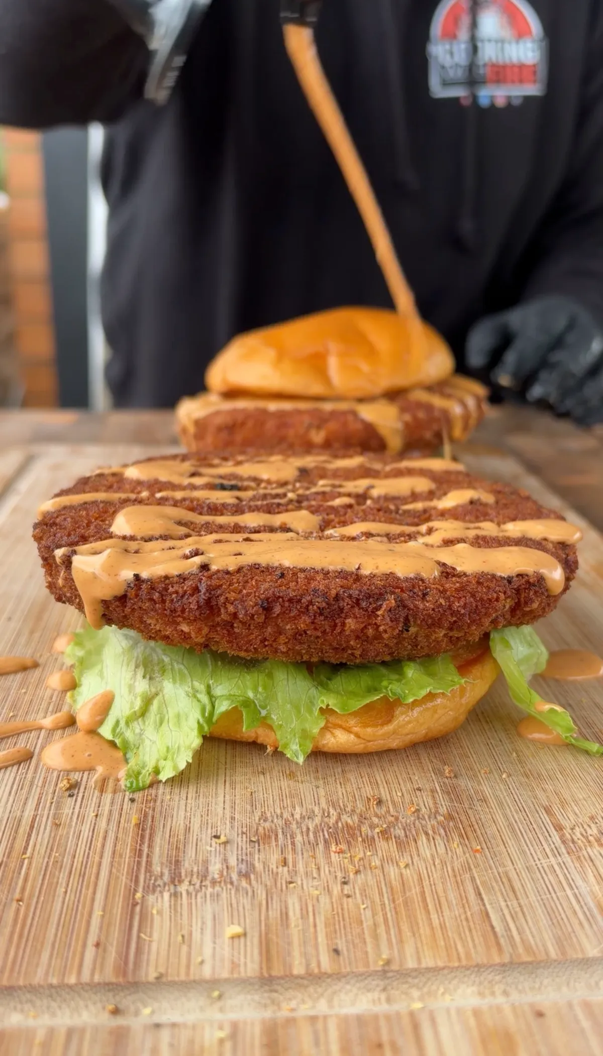 Crispy panko-breaded shrimp burger on brioche bun with lettuce and chipotle mayo drizzle on wooden board