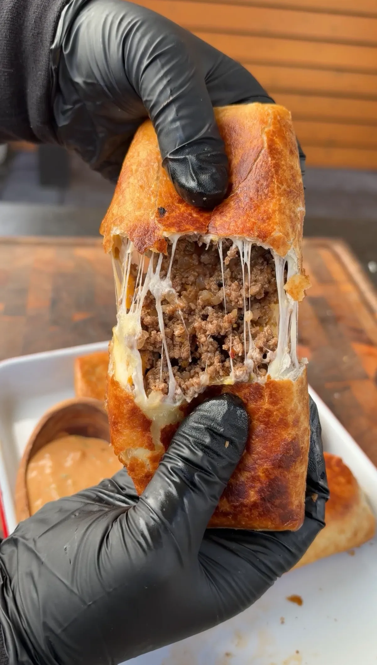 Fried burrito pulled apart showing seasoned 85/15 ground beef with melted pepper jack and Colby jack cheese strings
