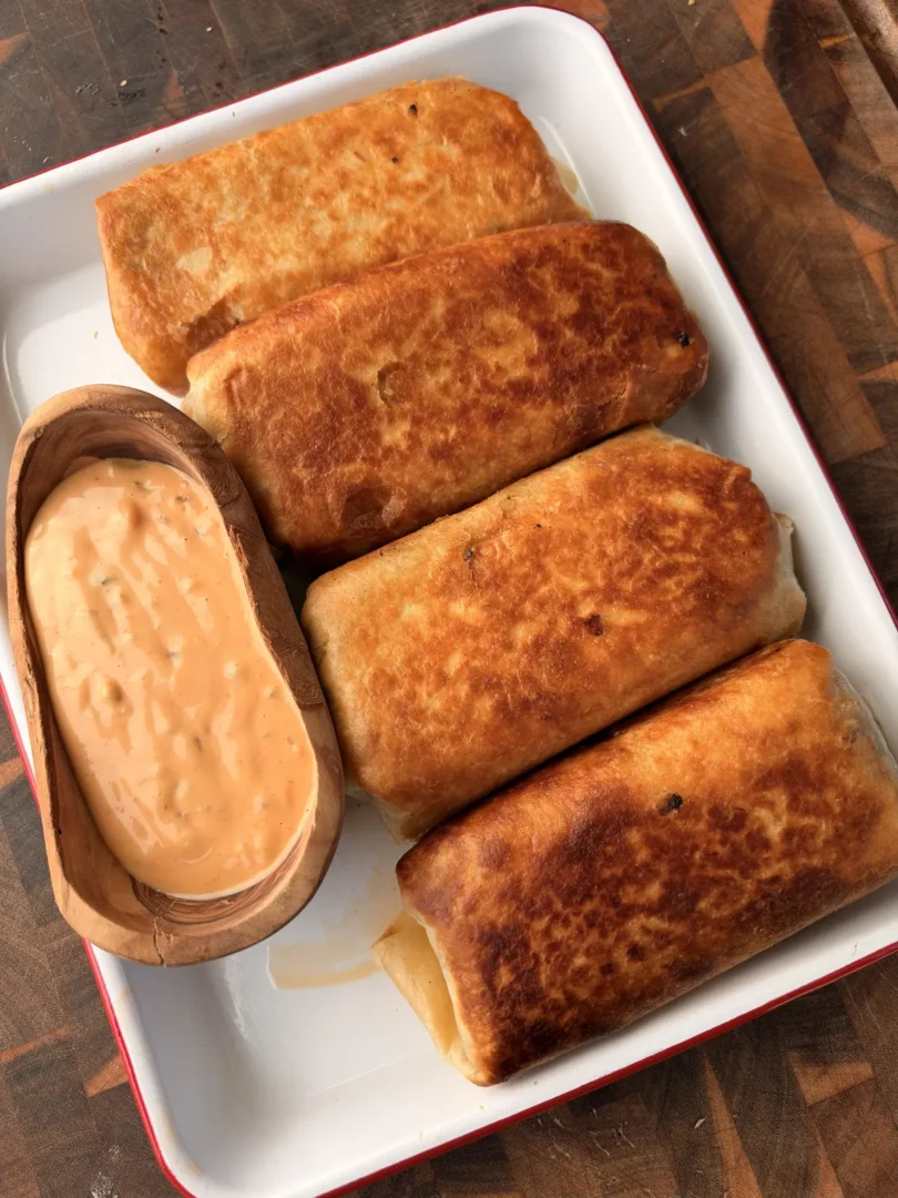 Five golden-brown fried cheeseburger burritos with pepper jack and Colby jack cheese served with creamy burger sauce