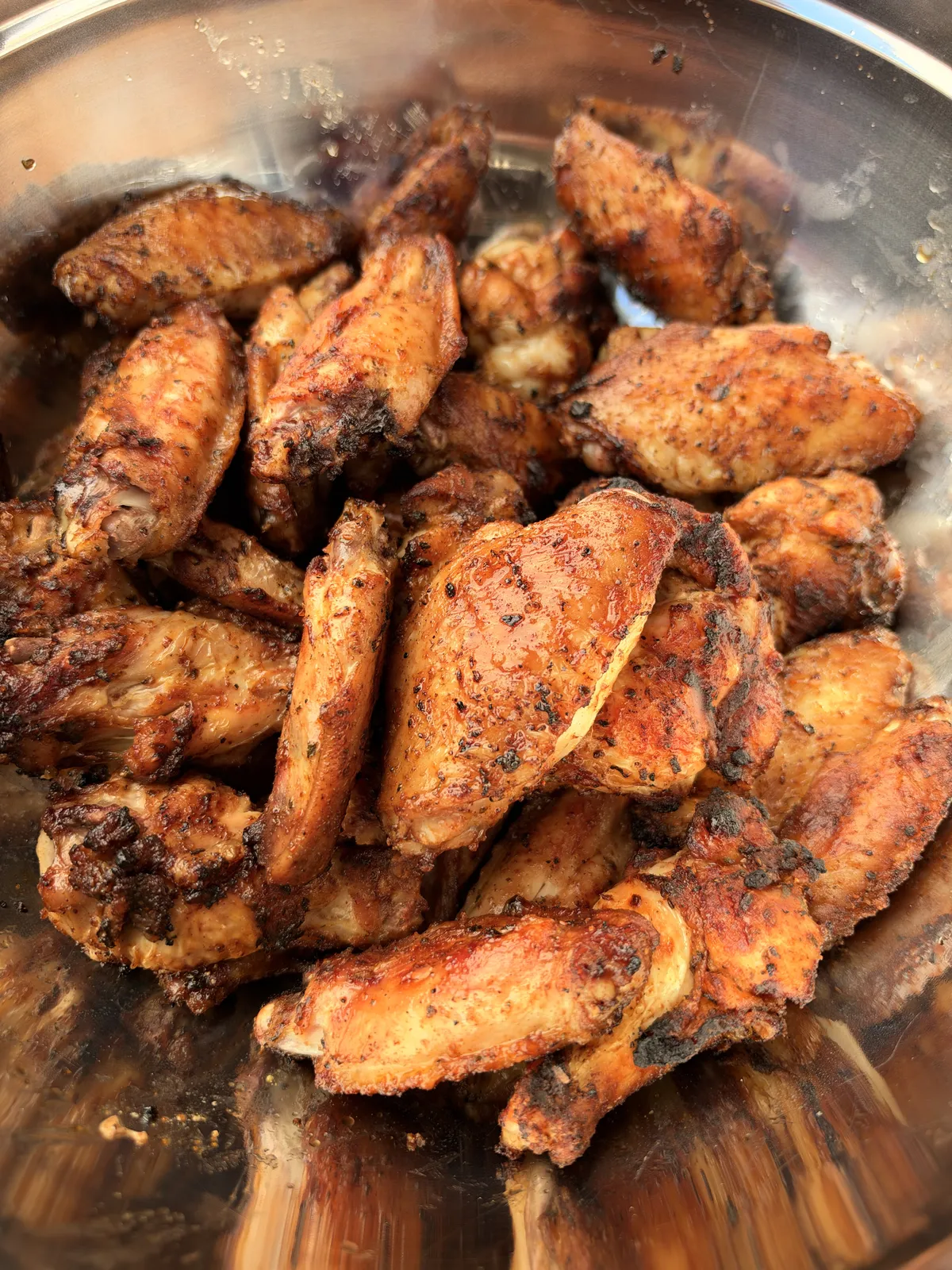 Crispy grilled chicken wings in a stainless steel bowl, coated in sticky pineapple habanero glaze