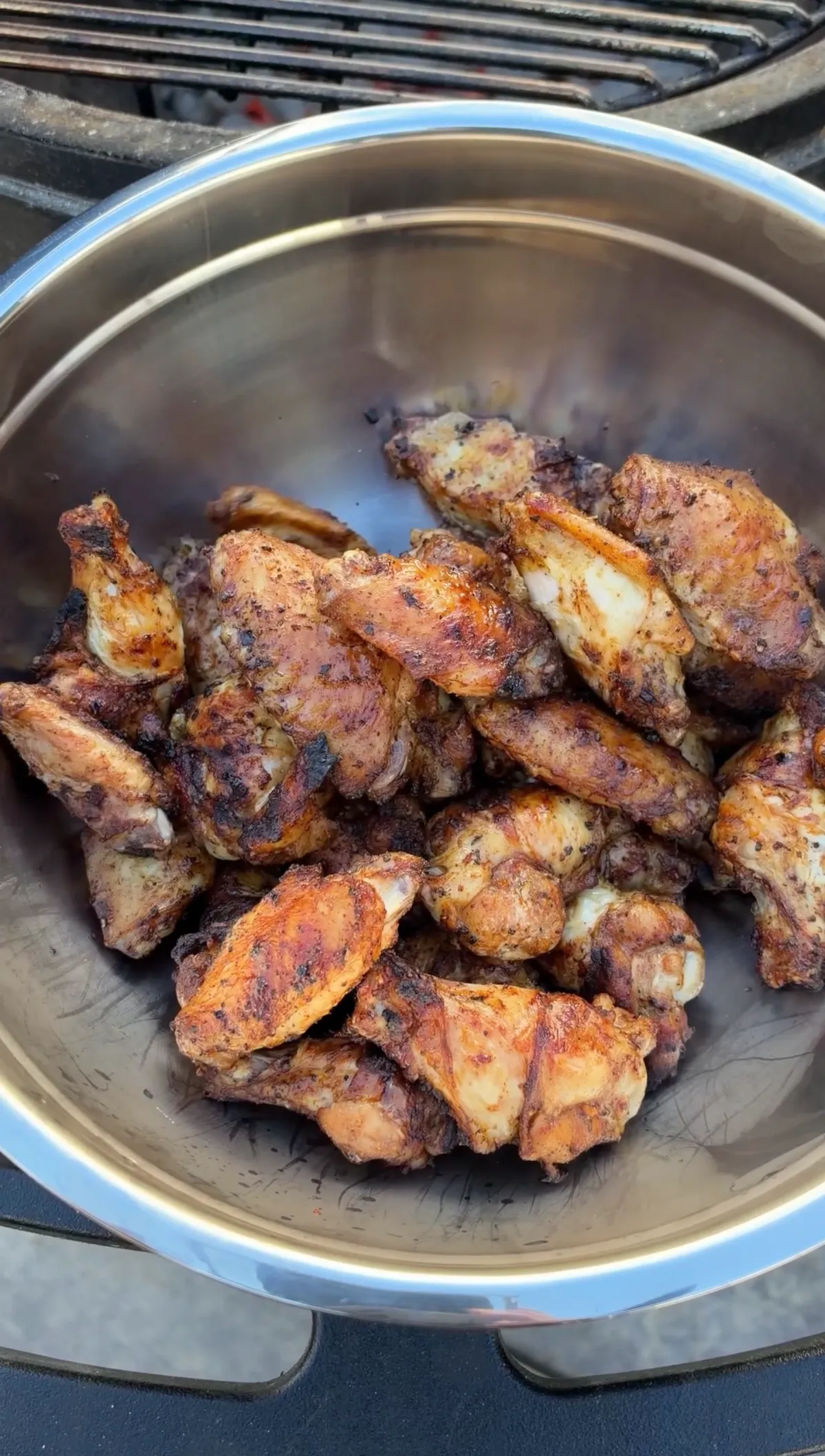 Crispy grilled chicken wings seasoned with poultry seasoning piled in a stainless steel bowl, ready to be tossed in pineapple habanero glaze