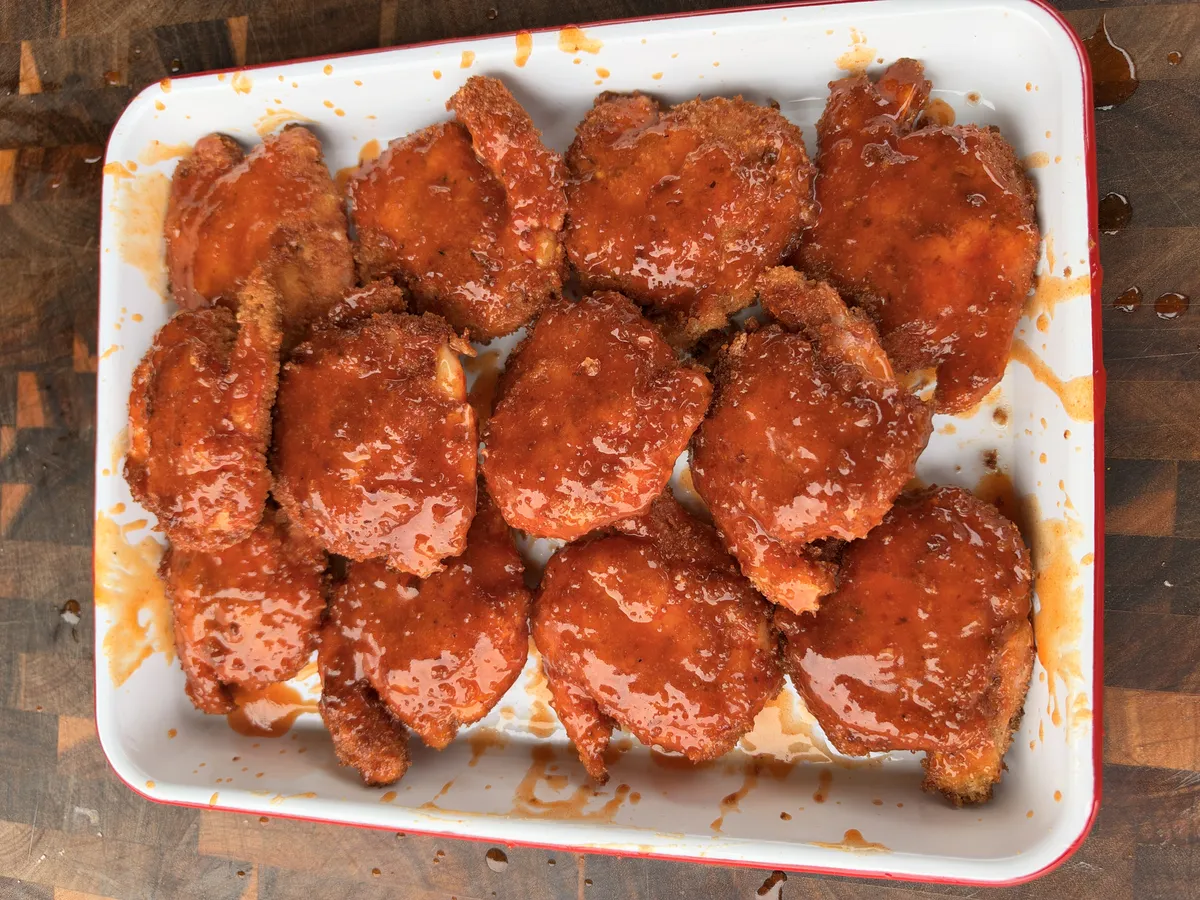 Crispy panko-breaded fried shrimp brushed with hot honey buffalo sauce on a white serving platter