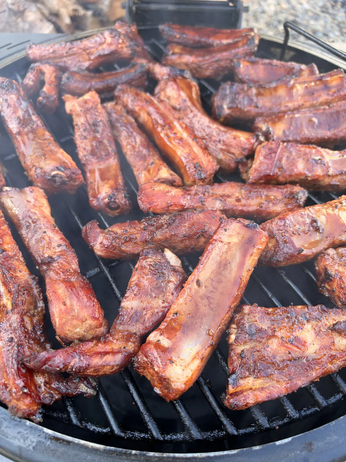 Individual St. Louis-style pork ribs developing a crust on smoker grates at 300–350°F during hot-and-fast smoking