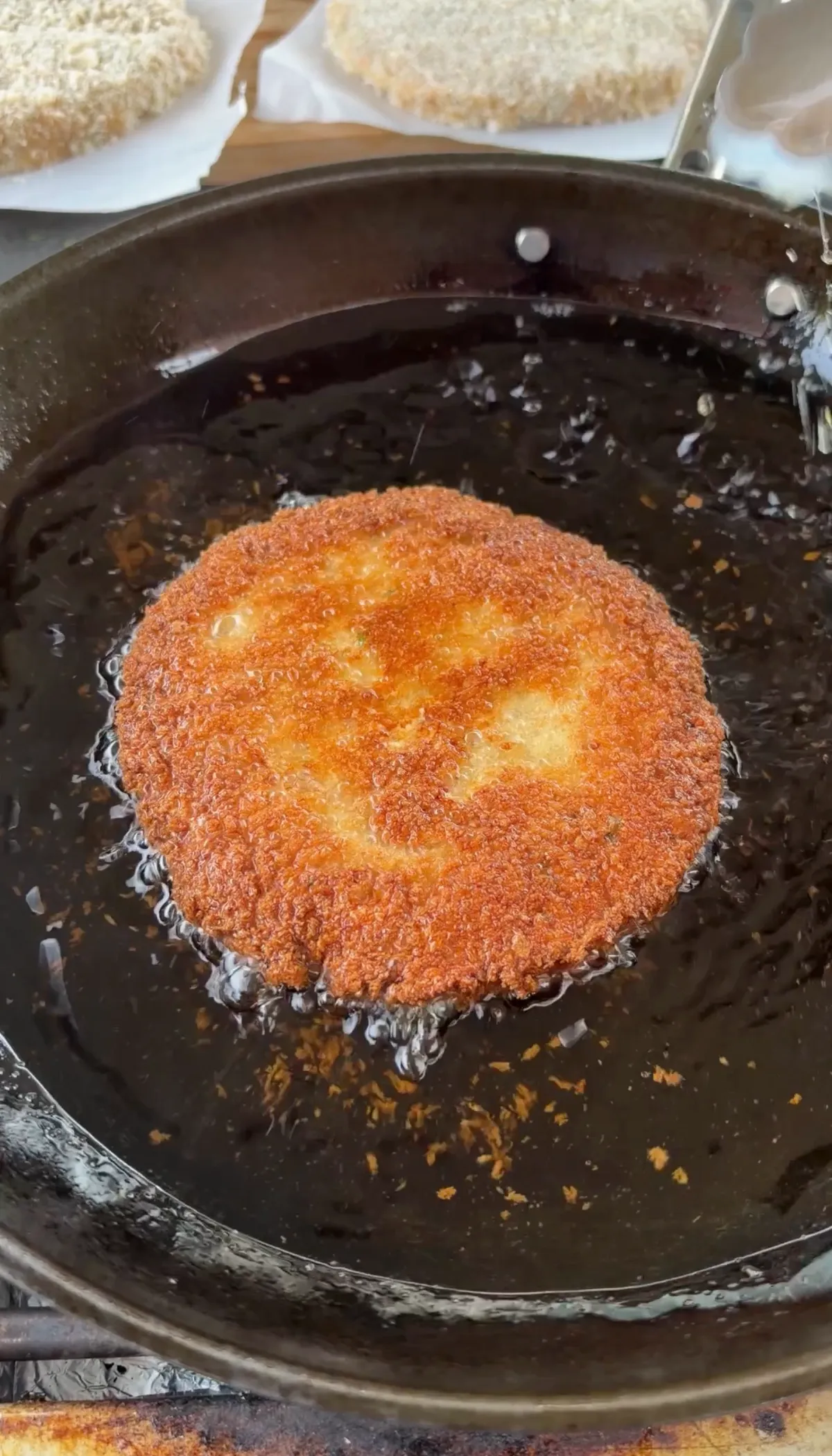 Golden panko-breaded shrimp burger patty frying in hot oil at 350°F in a shallow pan