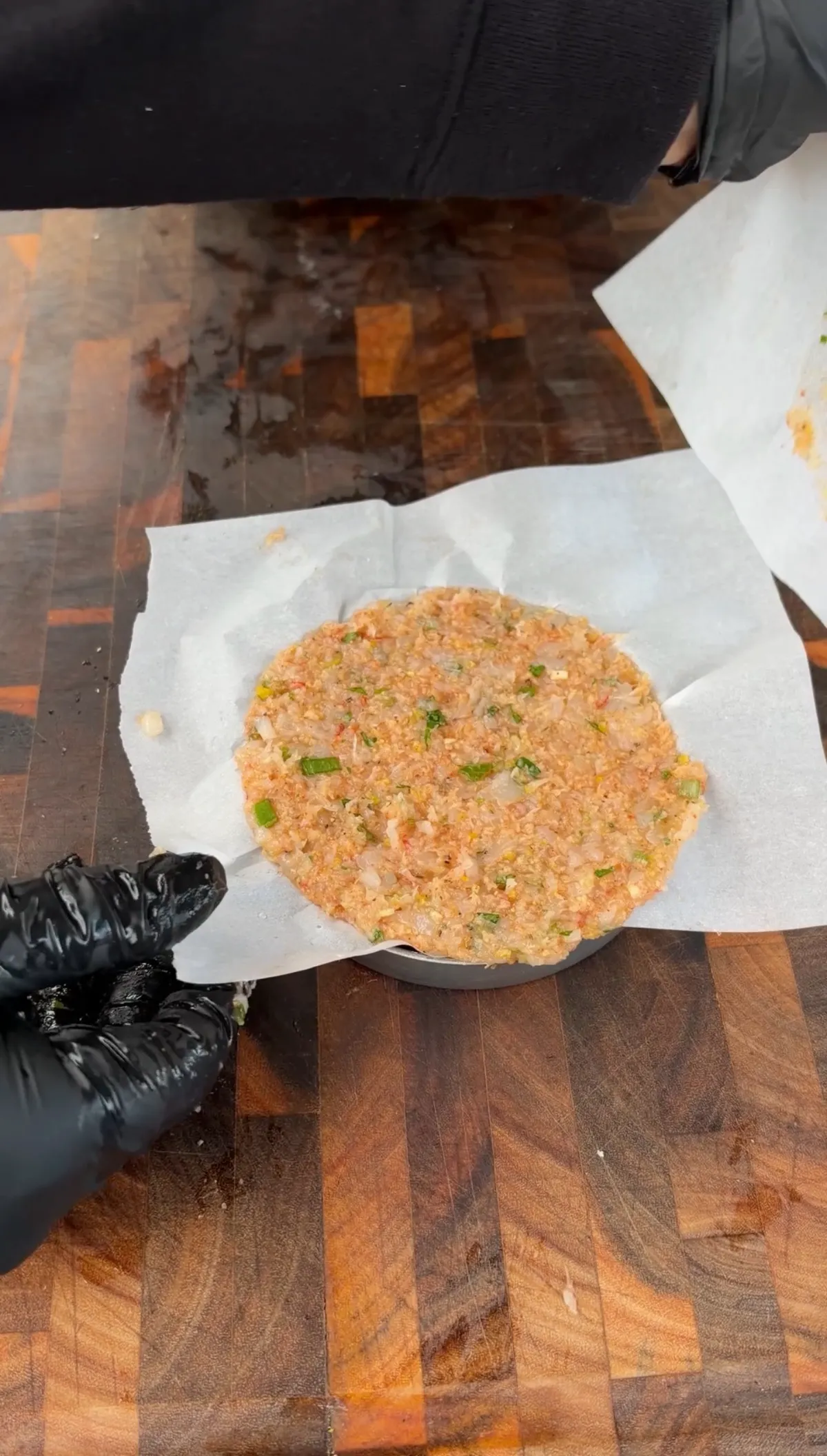 Raw Argentine shrimp burger patty with green onions and smoked paprika pressed in a burger mold on parchment paper