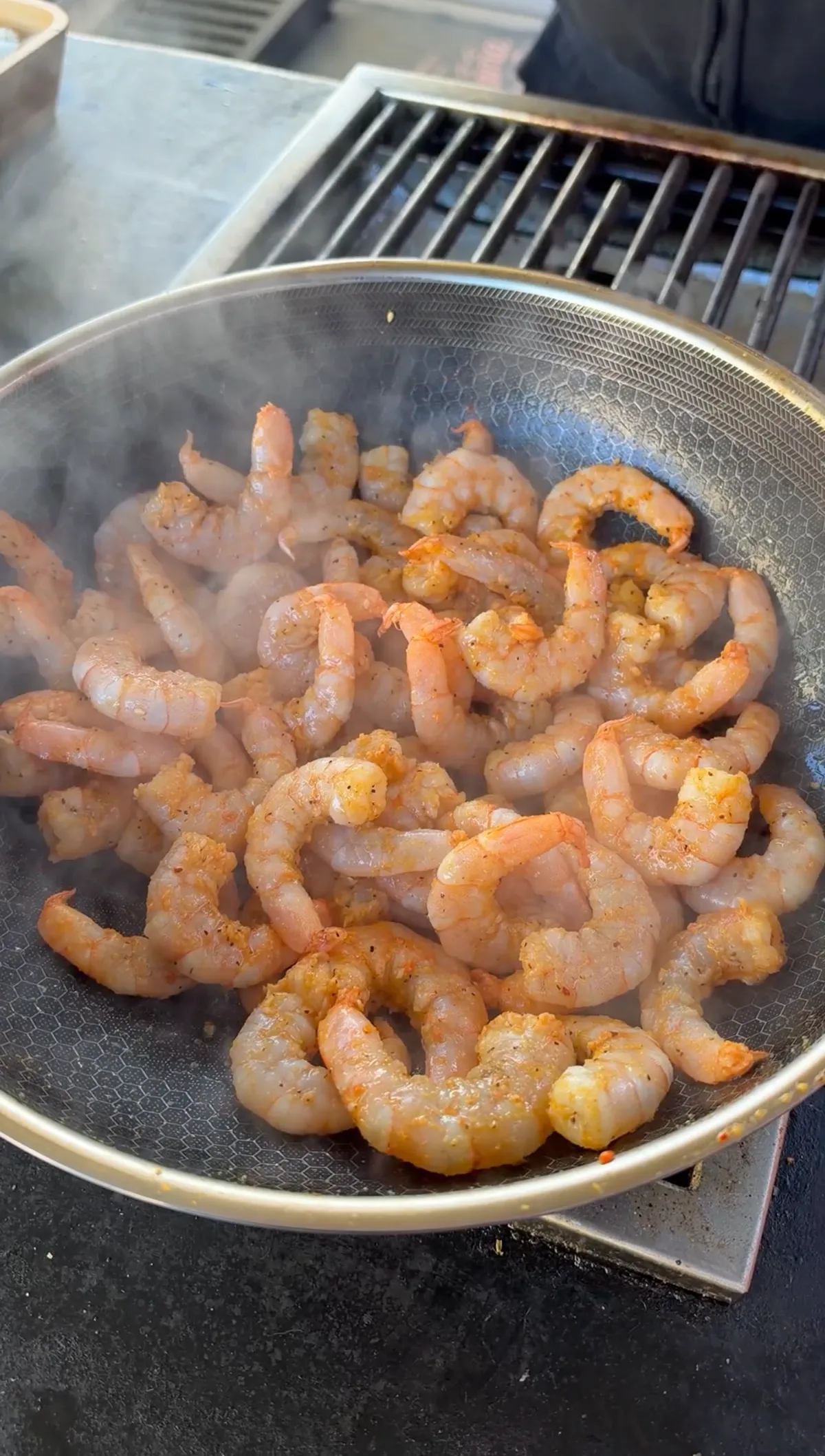 Seasoned shrimp cooking in a wok over high heat, turning pink with steam rising, step 3 of shrimp fried rice