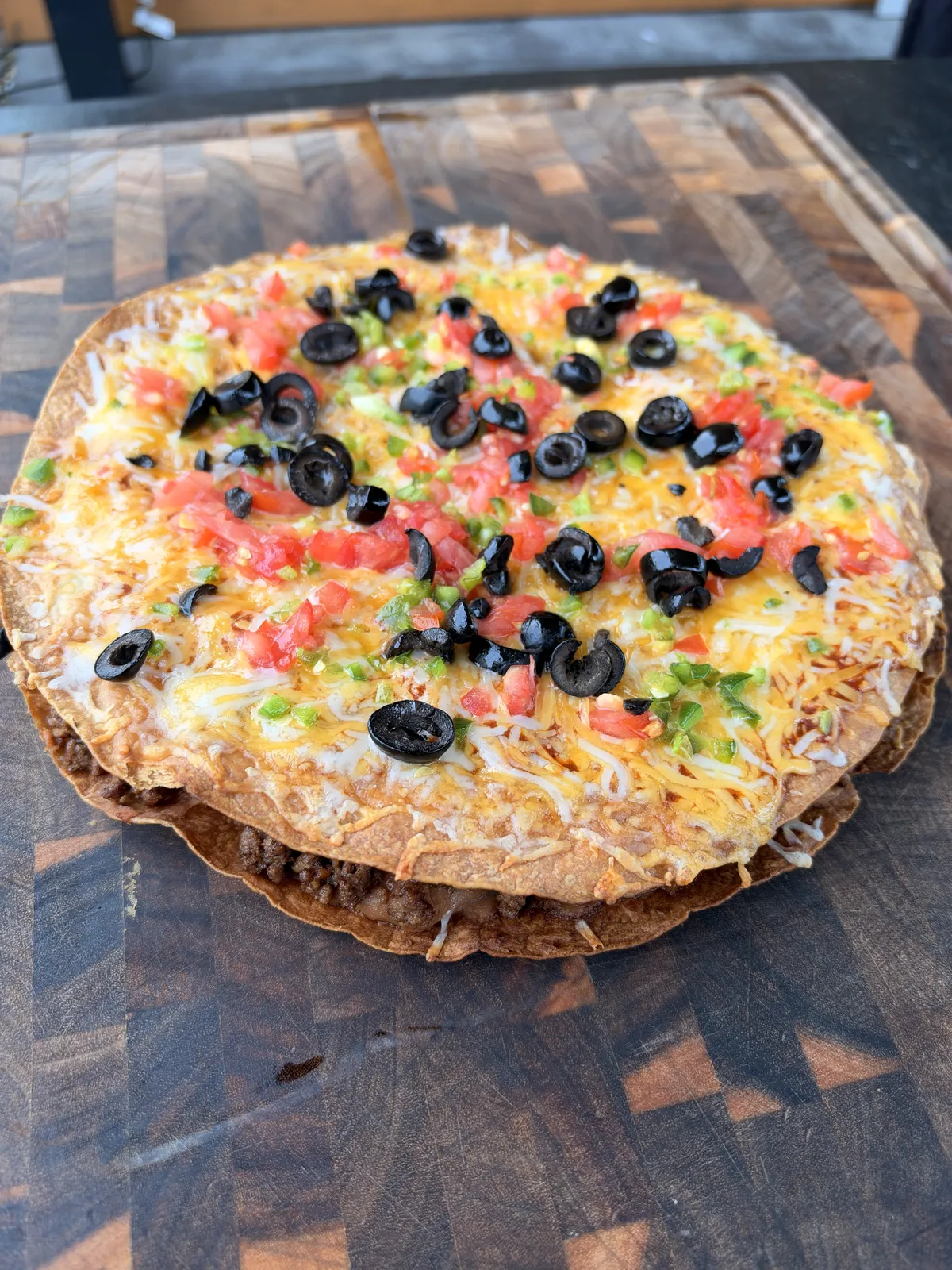Taco Bell copycat Mexican pizza with melted Colby Jack cheese, diced tomatoes, sliced black olives, and jalapeños on crispy flour tortillas