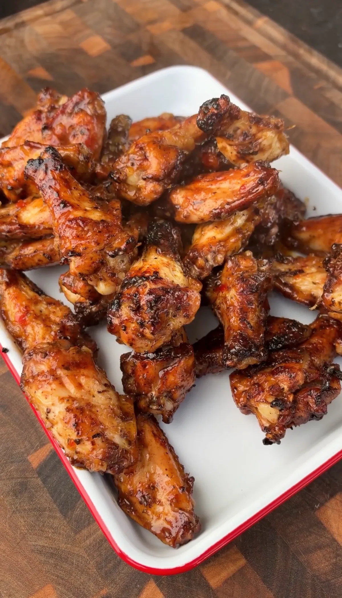 Pineapple habanero grilled chicken wings coated in sticky sweet-and-spicy glaze piled on a white enamel tray