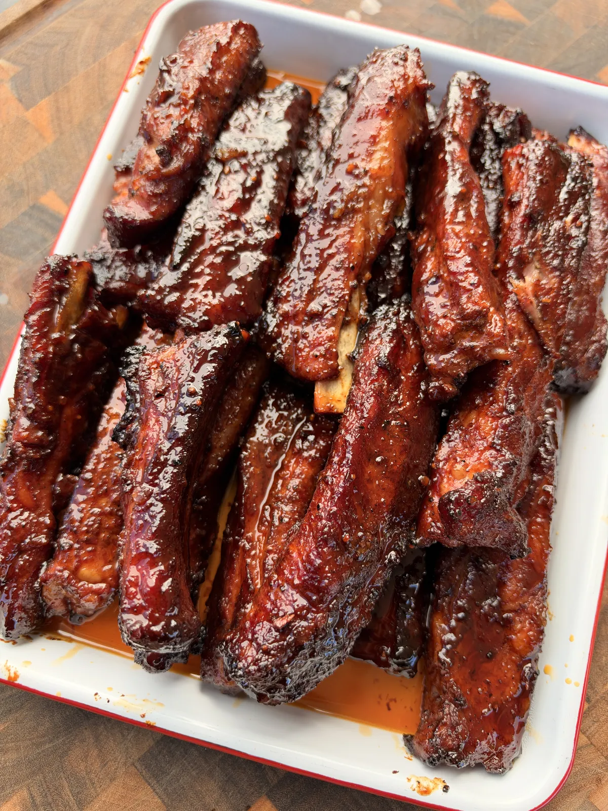 Sticky smoked St. Louis-style pork party ribs coated in glossy brown sugar honey barbecue sauce in a white tray